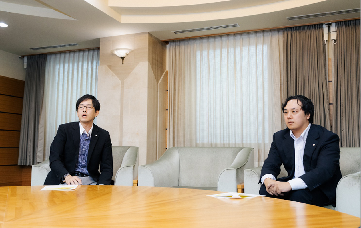 腰掛けに座り、インタビューを受ける両名